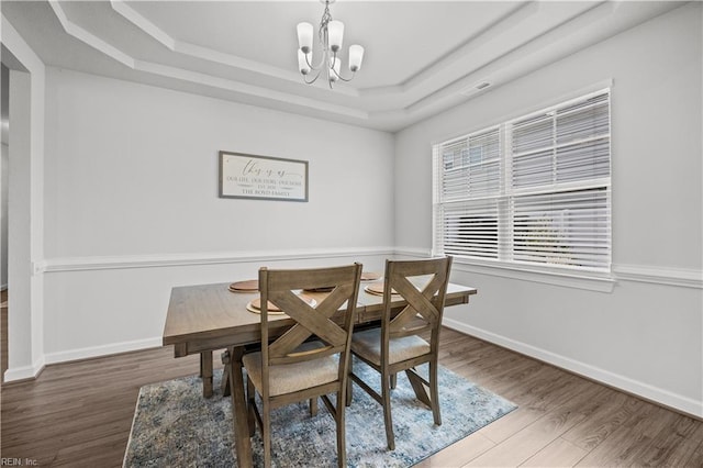 dining space featuring a tray ceiling, hardwood / wood-style floors, and a notable chandelier