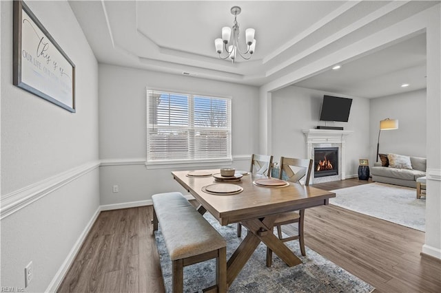 dining room with a chandelier, a tray ceiling, and dark hardwood / wood-style flooring