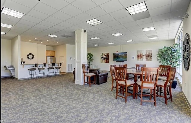 dining area with a paneled ceiling, decorative columns, and carpet