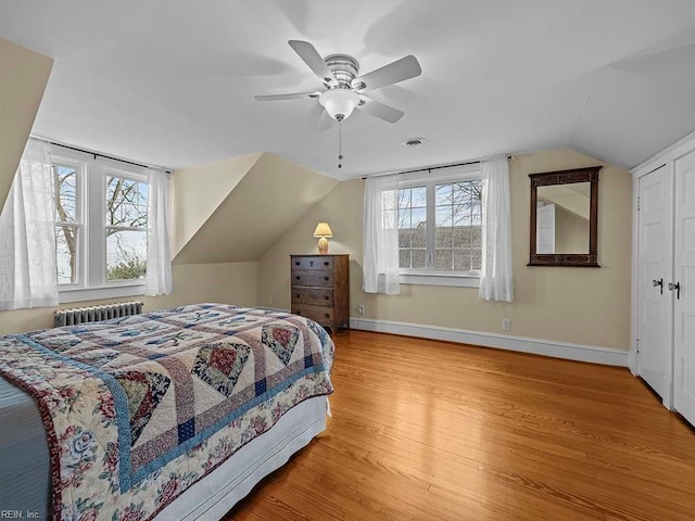bedroom featuring light hardwood / wood-style flooring, radiator heating unit, lofted ceiling, and ceiling fan