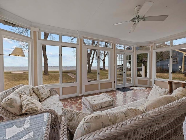 sunroom with a wealth of natural light, french doors, ceiling fan, and a water view