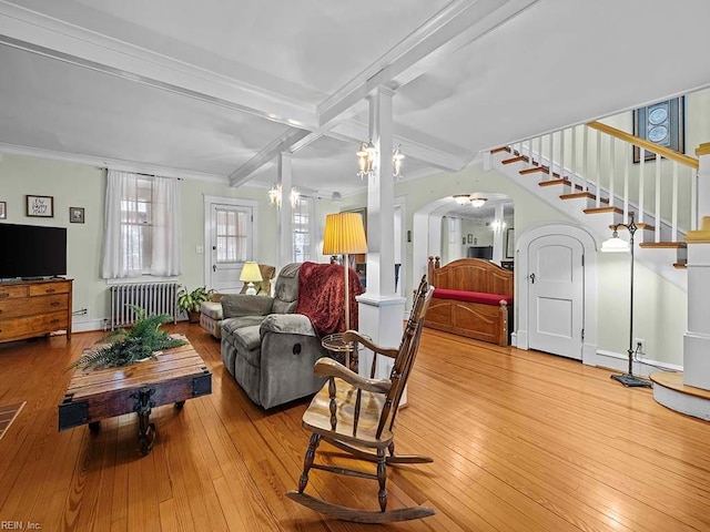 living room featuring radiator, decorative columns, wood-type flooring, ornamental molding, and beam ceiling