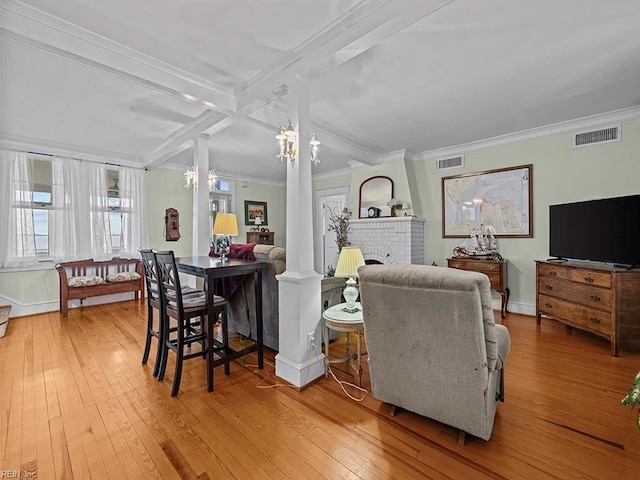 living room featuring crown molding, beam ceiling, light hardwood / wood-style flooring, and ornate columns