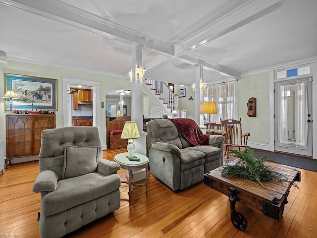 living room featuring ornamental molding, beam ceiling, a chandelier, and light hardwood / wood-style floors