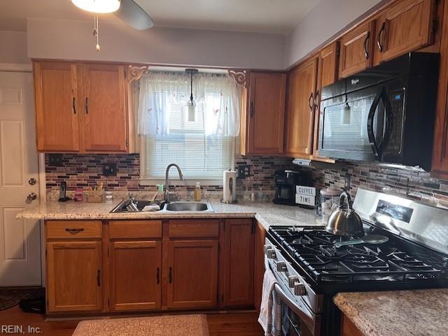 kitchen with decorative light fixtures, gas stove, backsplash, and sink