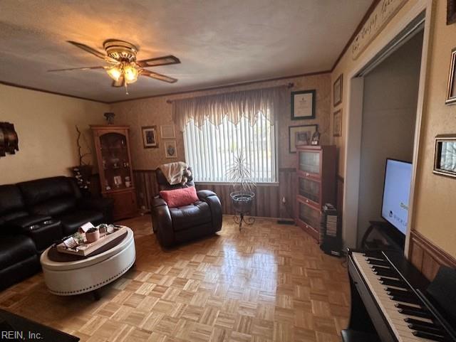 living room with ornamental molding, ceiling fan, and light parquet floors