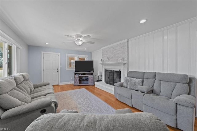 living room featuring a fireplace, ceiling fan, and light hardwood / wood-style flooring