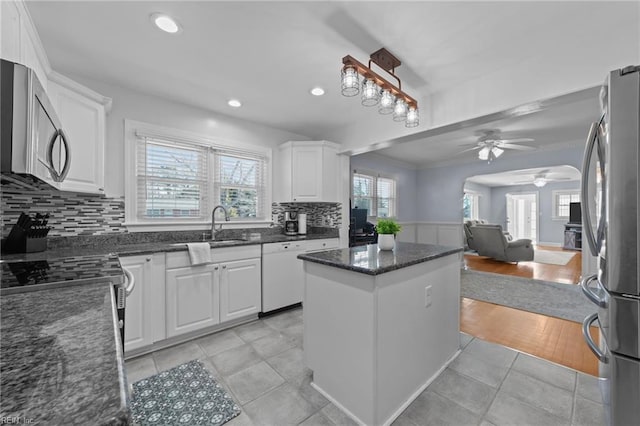 kitchen featuring pendant lighting, stainless steel appliances, dark stone counters, and white cabinets