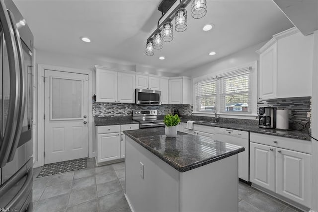 kitchen with a center island, hanging light fixtures, sink, appliances with stainless steel finishes, and white cabinets