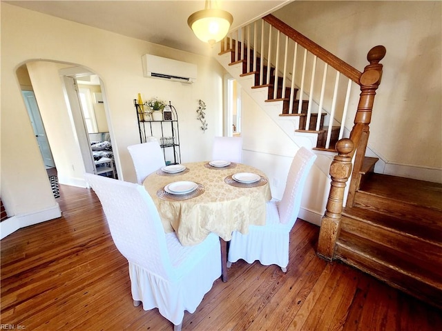 dining space with a wall unit AC and dark wood-type flooring