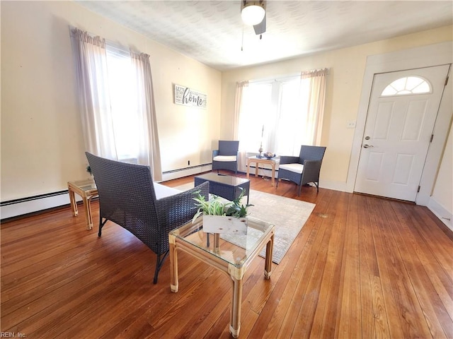 living room featuring ceiling fan, wood-type flooring, and baseboard heating