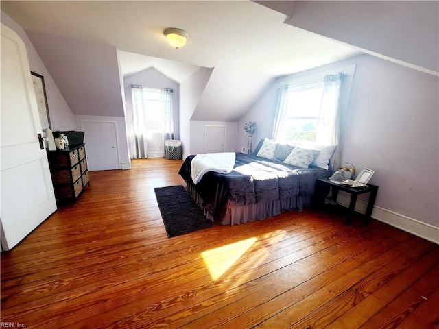 bedroom featuring multiple windows, lofted ceiling, and wood-type flooring