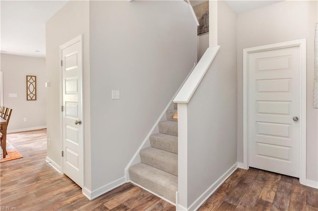 staircase featuring wood finished floors and baseboards