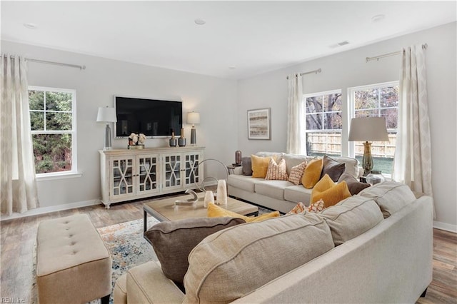 living room with light wood-type flooring, visible vents, and plenty of natural light