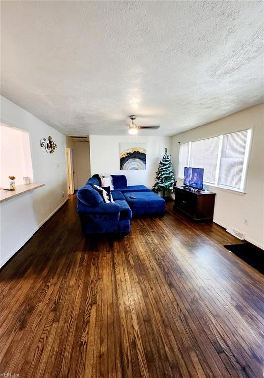 bedroom with ceiling fan, dark wood-type flooring, and a textured ceiling