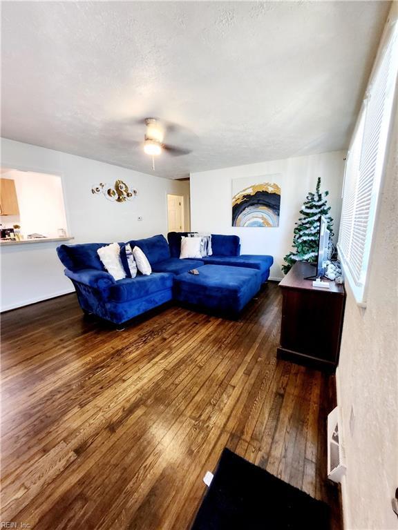 living room with ceiling fan, dark wood-type flooring, and a textured ceiling