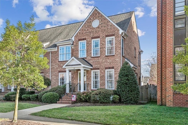 view of front of house with brick siding, fence, and a front lawn