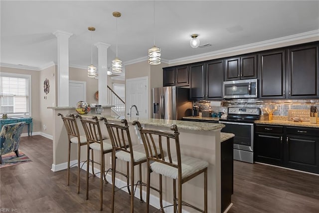 kitchen with appliances with stainless steel finishes, decorative backsplash, a kitchen bar, and pendant lighting