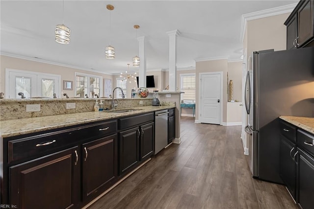 kitchen featuring pendant lighting, light stone counters, stainless steel appliances, a sink, and crown molding