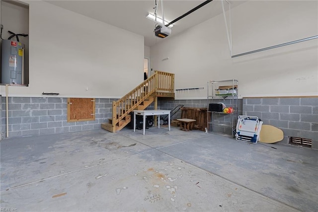 garage featuring concrete block wall, water heater, and a garage door opener