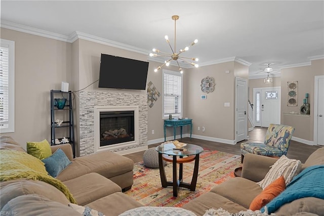 living room featuring baseboards, a tiled fireplace, ornamental molding, wood finished floors, and a notable chandelier