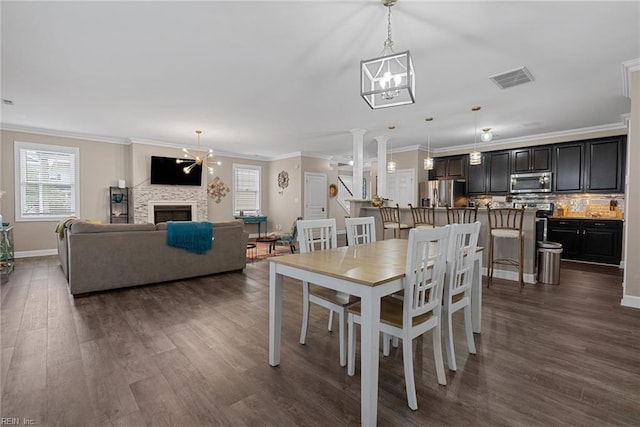 dining room featuring a fireplace, dark wood finished floors, visible vents, and an inviting chandelier