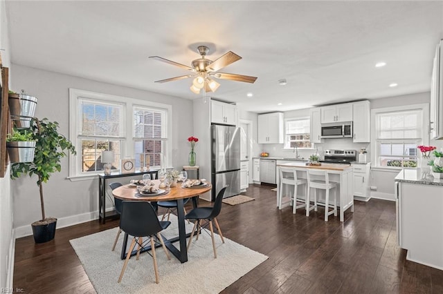 dining area with ceiling fan, sink, and dark hardwood / wood-style floors