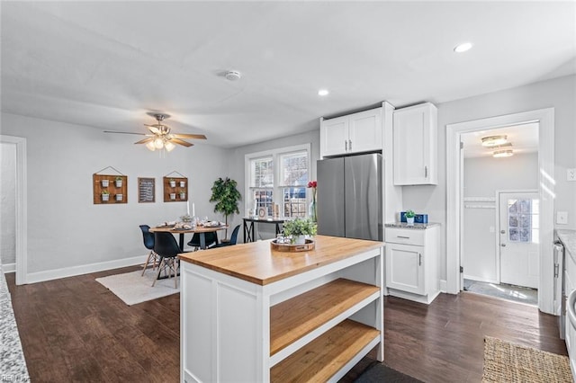 kitchen with a center island, white cabinetry, dark hardwood / wood-style floors, and stainless steel fridge