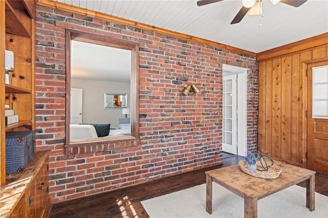 living room featuring hardwood / wood-style floors, ceiling fan, and brick wall