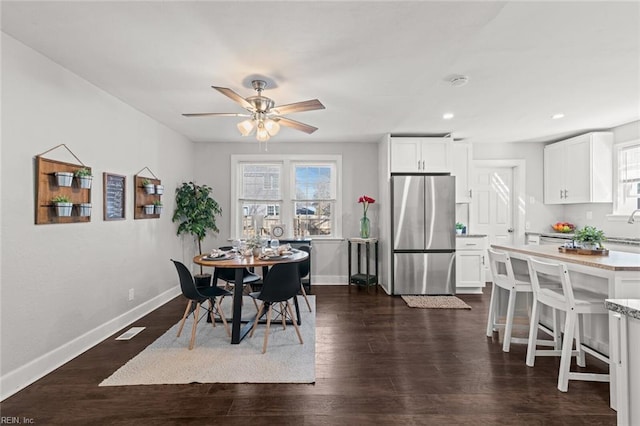 dining space with ceiling fan, plenty of natural light, and dark wood-type flooring