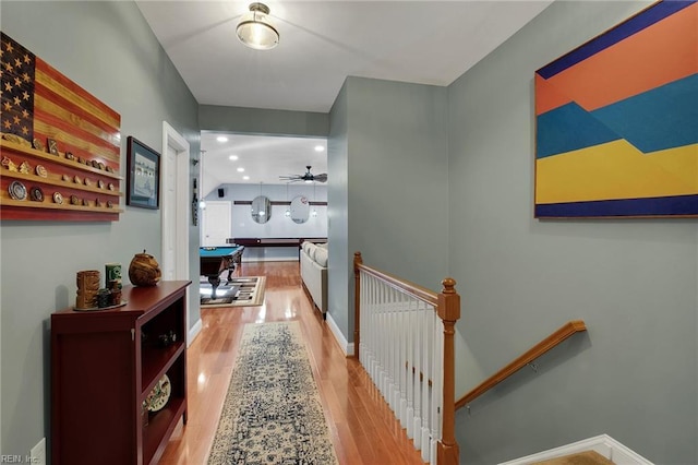 corridor featuring recessed lighting, baseboards, wood finished floors, and an upstairs landing