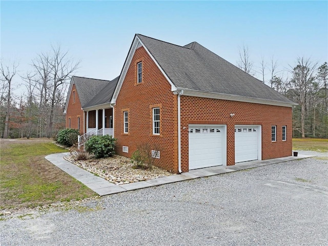 view of property exterior featuring a garage, driveway, brick siding, and crawl space