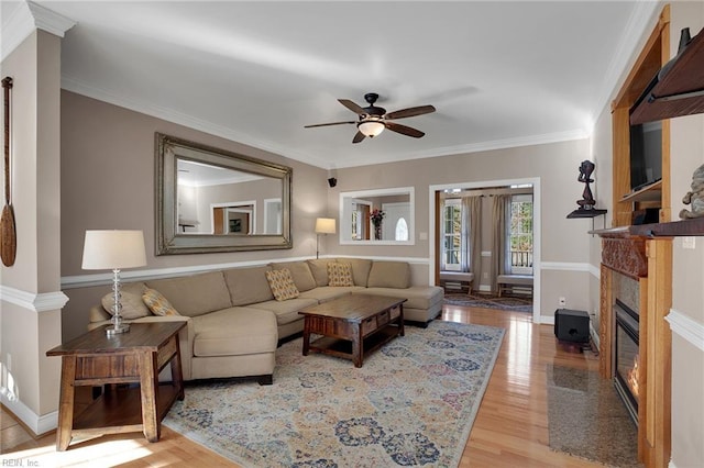 living area with baseboards, light wood-type flooring, a fireplace with flush hearth, and crown molding