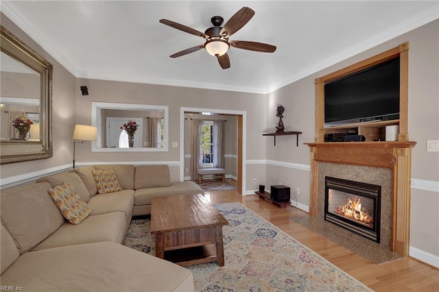 living room with ornamental molding, a fireplace with flush hearth, light wood-style flooring, and baseboards