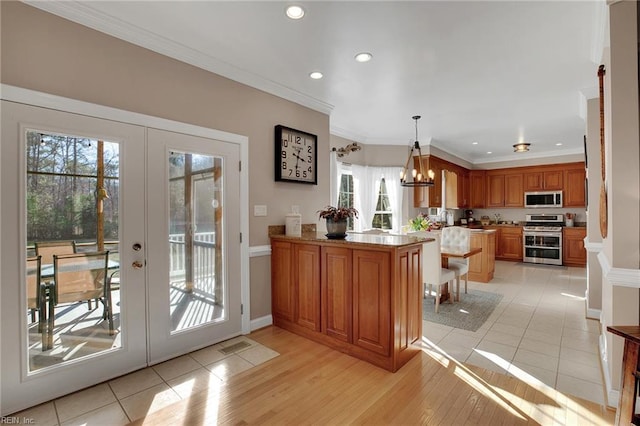 kitchen featuring a peninsula, stainless steel appliances, french doors, brown cabinetry, and pendant lighting