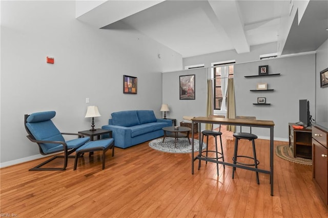 living room with beamed ceiling and light hardwood / wood-style flooring