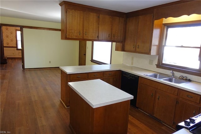 kitchen featuring dishwasher, dark wood-type flooring, a kitchen island, sink, and kitchen peninsula