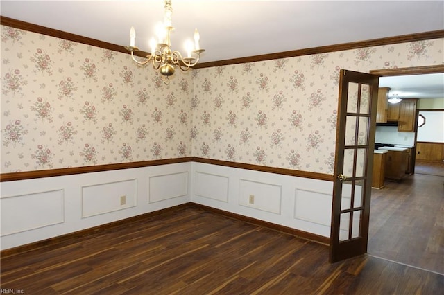 unfurnished room featuring ornamental molding, an inviting chandelier, and dark hardwood / wood-style flooring