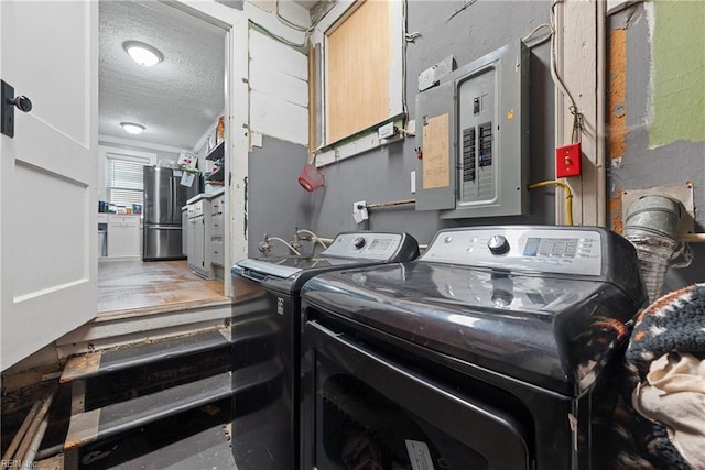 clothes washing area featuring electric panel, independent washer and dryer, and a textured ceiling