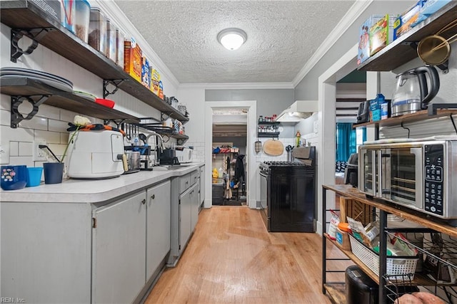 kitchen featuring crown molding, black range with gas stovetop, a textured ceiling, and light wood-type flooring