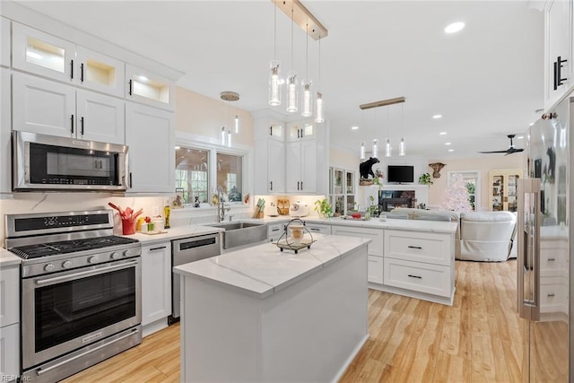 kitchen featuring sink, a center island, pendant lighting, stainless steel appliances, and white cabinets