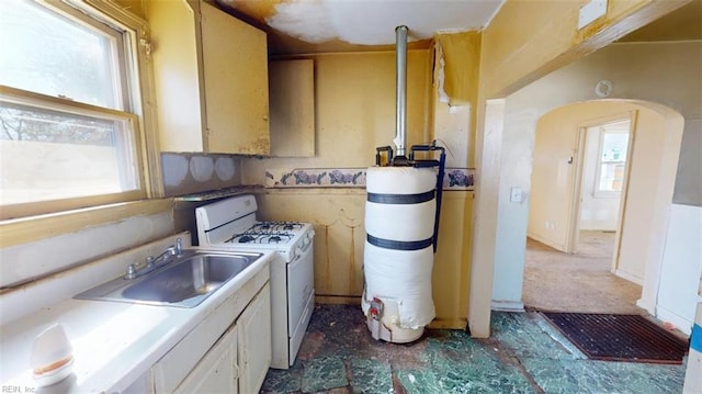 kitchen with a sink, white gas stove, arched walkways, and light countertops