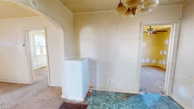 empty room with arched walkways and light colored carpet