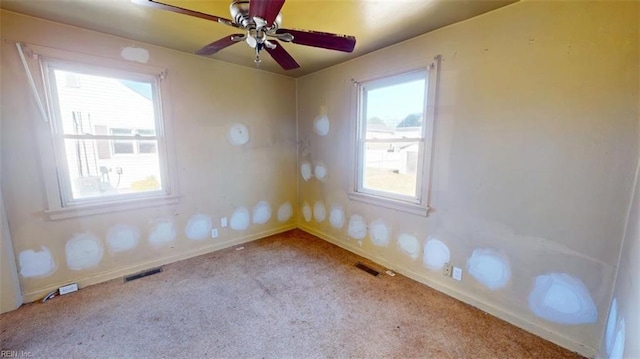 spare room with light carpet, ceiling fan, visible vents, and baseboards