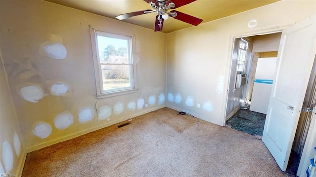 spare room featuring light carpet, visible vents, and a ceiling fan