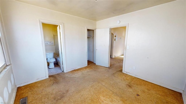 unfurnished bedroom with ensuite bath, visible vents, a closet, and light colored carpet