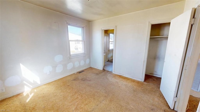 unfurnished bedroom with a closet, visible vents, and light carpet