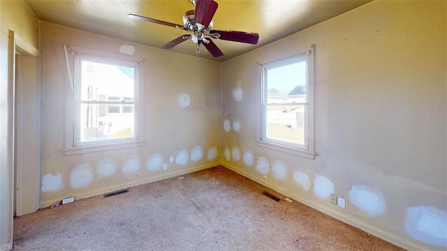 empty room with a healthy amount of sunlight, visible vents, and light colored carpet