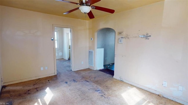 empty room featuring arched walkways, baseboards, visible vents, and a ceiling fan