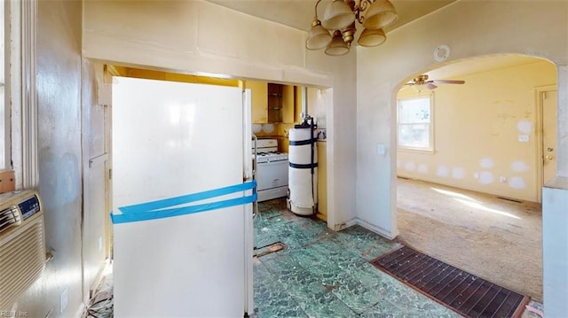 kitchen featuring arched walkways, a ceiling fan, freestanding refrigerator, carpet flooring, and washer / dryer